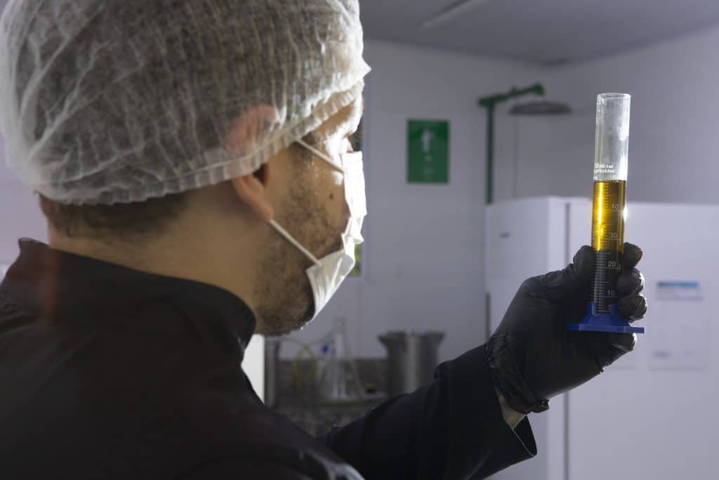 Técnico do laboratório da APEPI analisando óleo de flor de cannabis em proveta