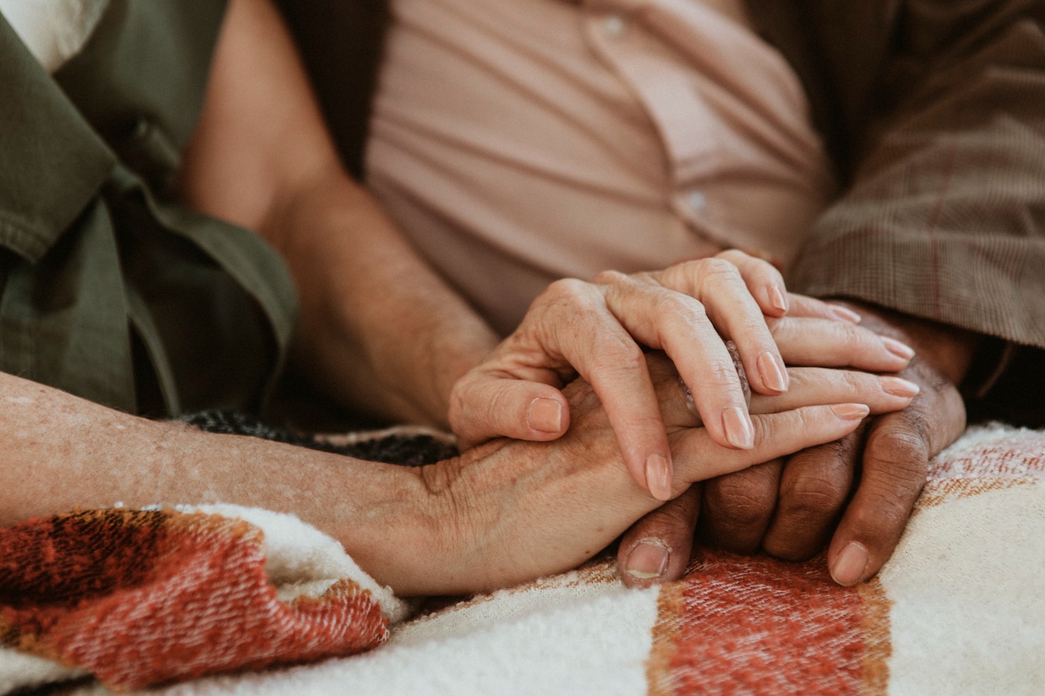 Mãos entrelaçadas de idoso e cuidador em gesto de afeto e apoio no contexto do uso de canabidiol para Alzheimer.